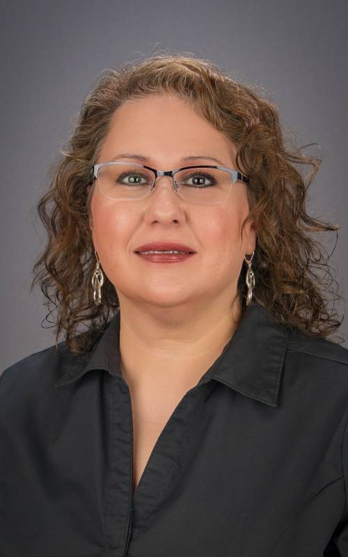 A woman with curly hair wearing glasses and a black shirt.